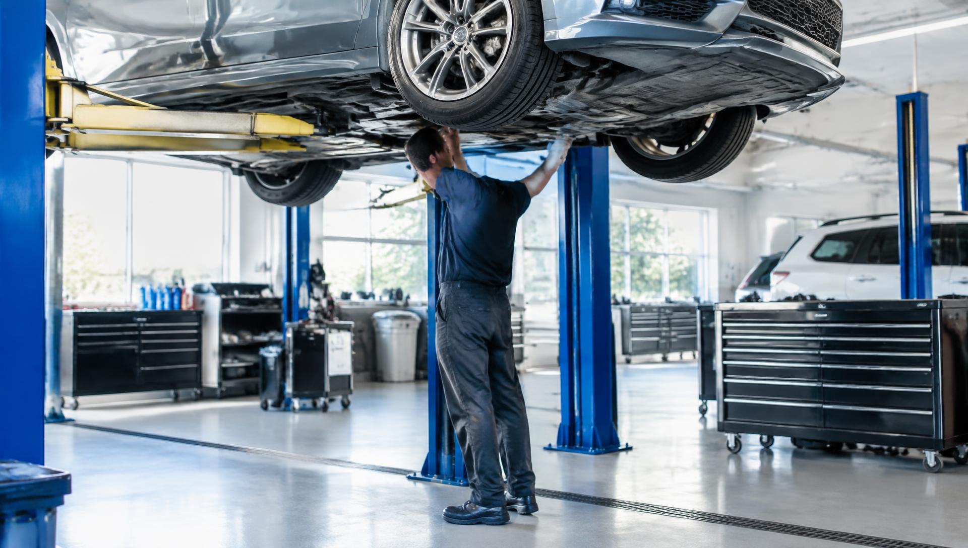 Technician working under a lifted car in the Saga Autos service bay